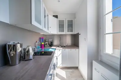 a kitchen with white cabinets and a large window at Beautiful studio rue d'Antibes in Cannes