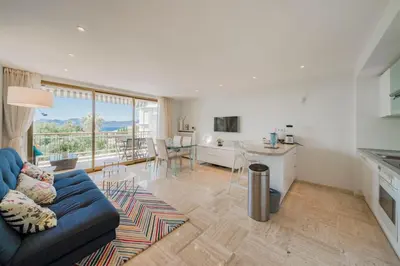 a living room with a blue couch and a kitchen at Wonderful 2 bedrooms with sea view and pool ! in Cannes