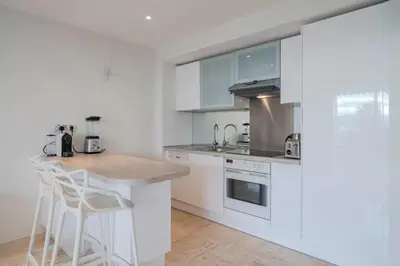 a kitchen with white cabinets and a counter with stools at Wonderful 2 bedrooms with sea view and pool ! in Cannes