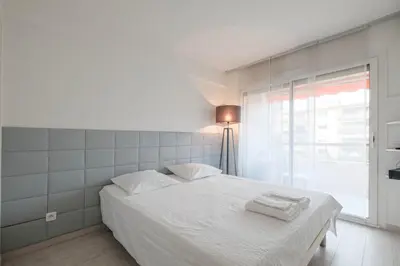 a bedroom with a bed with white sheets and a window at Wonderful 1 bedroom 3 min walk to the Croisette! in Cannes