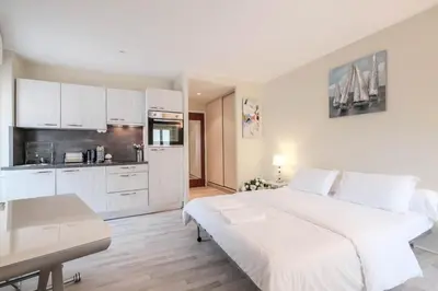 a white bedroom with a large bed and a kitchen at Cozystay 1087 - Charming studio historic Suquet in Cannes