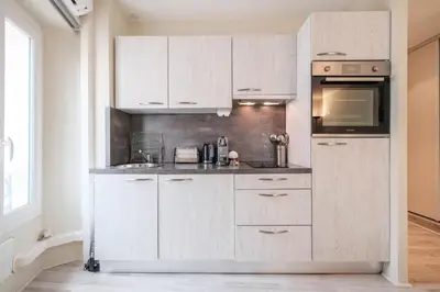 a kitchen with white cabinets and a microwave at Cozystay 1087 - Charming studio historic Suquet in Cannes