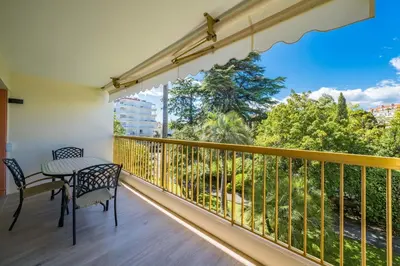 a balcony with a table and chairs and a large window at Beautiful studio with balcony in Cannes in Cannes