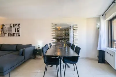 a dining room with a table and chairs and a couch at 4 pièces sur deux niveaux au cœur de Cannes in Cannes
