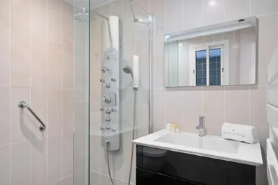 a white bathroom with a sink and a shower at Agréable studio à deux pas de la Croisette in Cannes