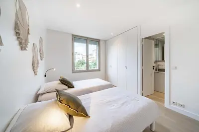 two beds in a white bedroom with a window at Superbe appartement 5 pièces sur la Croisette in Cannes