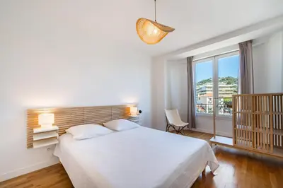 a bedroom with a white bed and a large window at Superb two-bedroom near the Croisette in Cannes