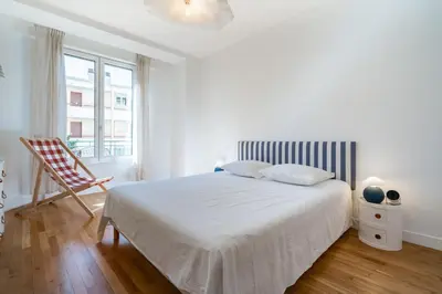 a white bedroom with a bed and a chair at Superb two-bedroom near the Croisette in Cannes