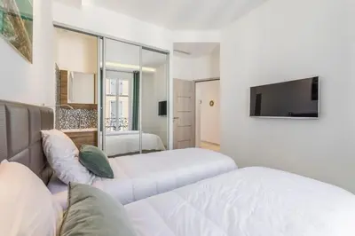 a white bedroom with two beds and a tv at Cozystay 1243 Port & Sea View Cannes in Cannes