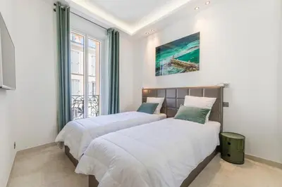 two beds in a bedroom with white walls and a window at Cozystay 1243 Port & Sea View Cannes in Cannes