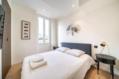 a white bedroom with a large bed with two pillows at Pleasant 2 bedroom in the heart of Cannes in Cannes
