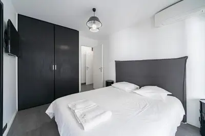 a bedroom with a large white bed with a black headboard at COZYSTAY - Brand new 3 bedrooms 2min walk to carlton hotel in Cannes