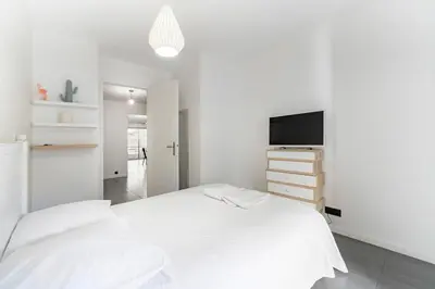 a white bedroom with a bed and a tv at COZYSTAY - Brand new 3 bedrooms 2min walk to carlton hotel in Cannes