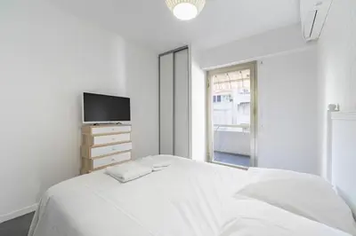 a white bedroom with a bed and a tv at COZYSTAY - Brand new 3 bedrooms 2min walk to carlton hotel in Cannes