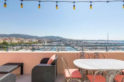 a balcony with tables and chairs and a view of a harbor at Cozystay 1674 - Gorgeous sea view 3-bedroom duplex in Cannes