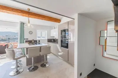 a kitchen with white cabinets and a table and chairs at Cozystay 1674 - Gorgeous sea view 3-bedroom duplex in Cannes