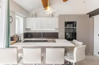 a kitchen with white cabinets and white chairs at Cozystay 1674 - Gorgeous sea view 3-bedroom duplex in Cannes