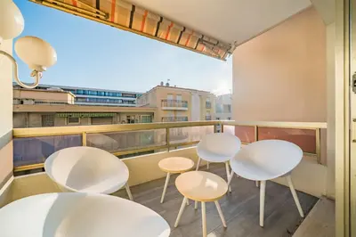 a balcony with four white chairs and tables at Apartment for 4 people in the heart of Cannes in Cannes