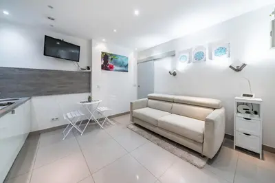 a white living room with a couch and a tv at Appartement Studio idéalement situé - Palais Miramar in Cannes