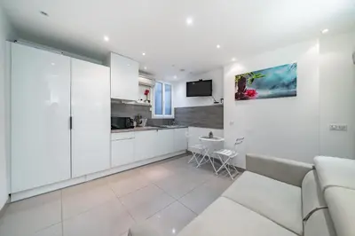 a white living room with a couch and a kitchen at Appartement Studio idéalement situé - Palais Miramar in Cannes
