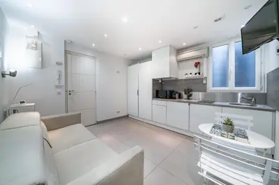 a white kitchen with a white couch and a table at Appartement Studio idéalement situé - Palais Miramar in Cannes