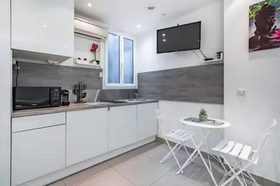 a kitchen with white cabinets and a table and a tv at Appartement Studio idéalement situé - Palais Miramar in Cannes