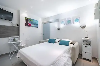 a white bedroom with a large bed and a desk at Appartement Studio idéalement situé - Palais Miramar in Cannes