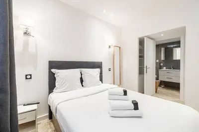 a white bedroom with a bed and a bathroom at 84 MEY - Apartment for 4 people near Croisette and Palais in Cannes
