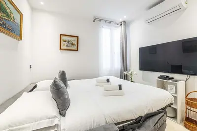 a white bedroom with a large bed and a tv at 84 MEY - Apartment for 4 people near Croisette and Palais in Cannes