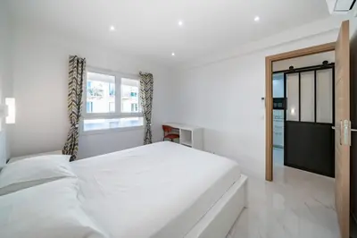 a white bedroom with a large bed and a window at Agréable 3 pièces rénové à deux pas de la croisette in Cannes