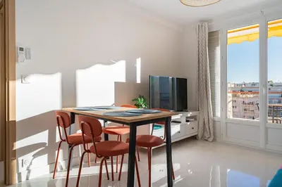 a dining room with a table with chairs and a television at Agréable 3 pièces rénové à deux pas de la croisette in Cannes
