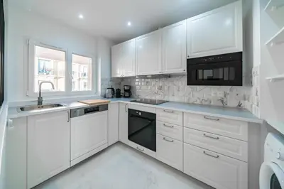 a white kitchen with white cabinets and a sink at Agréable 3 pièces rénové à deux pas de la croisette in Cannes