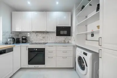 a kitchen with white cabinets and a washer and dryer at Agréable 3 pièces rénové à deux pas de la croisette in Cannes