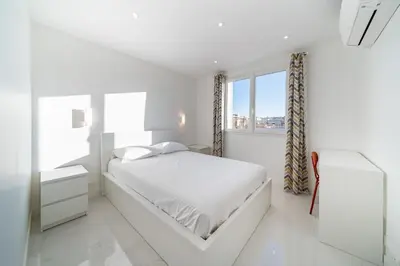 a white bedroom with a bed and a window at Agréable 3 pièces rénové à deux pas de la croisette in Cannes