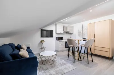 a living room with a blue couch and a kitchen at Renovated and Bright Studio 3P - Cannes in Cannes