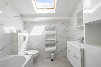 a white bathroom with a sink toilet and a skylight at Renovated and Bright Studio 3P - Cannes in Cannes