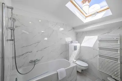 a white bathroom with a tub and a toilet at Renovated and Bright Studio 3P - Cannes in Cannes