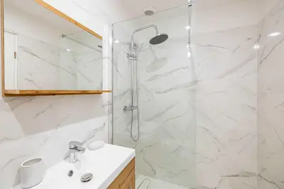 a white bathroom with a shower and a sink at Renovated and Bright Studio 4P - Cannes in Cannes