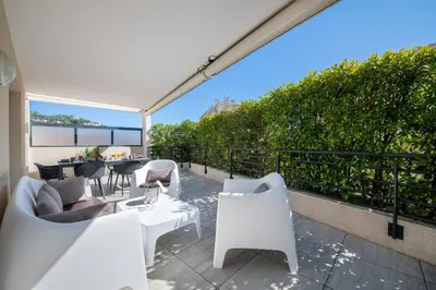 a patio with white chairs and tables on a balcony at 3-Br Rooftop with Jacuzzi & Parking Cannes in Cannes