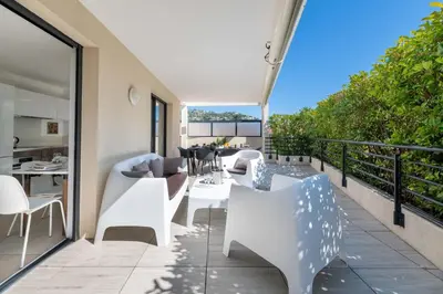 a balcony with white furniture and a dining table at 3-Br Rooftop with Jacuzzi & Parking Cannes in Cannes