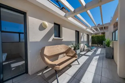 a patio with a wicker chair and a glass roof at 3-Br Rooftop with Jacuzzi & Parking Cannes in Cannes
