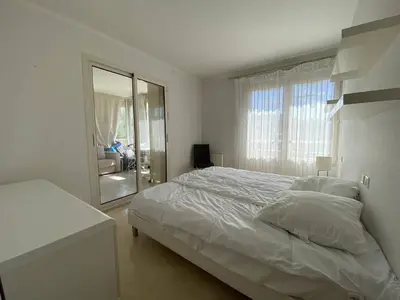 a white bedroom with a bed and a mirror at Cannes Proche Croisette - Appartement 3 pièces in Cannes