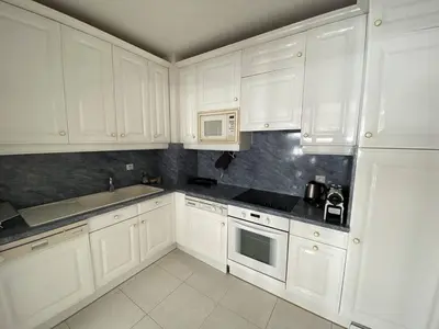 a white kitchen with white cabinets and appliances at Cannes Proche Croisette - Appartement 3 pièces in Cannes