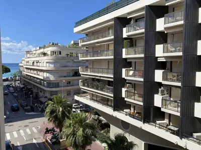 an apartment building with palm trees in front of a street at Cannes Proche Croisette - Appartement 3 pièces in Cannes