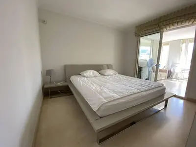 a bed in a white room with a large window at Cannes Proche Croisette - Appartement 3 pièces in Cannes
