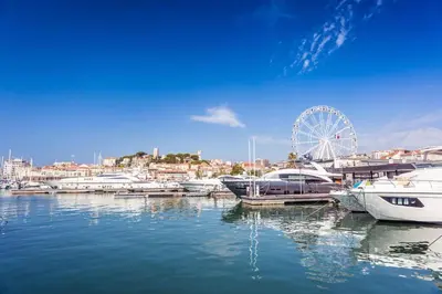 a group of boats docked in a harbor with a ferris wheel at Appartement Cannes Hyper Centre in Cannes