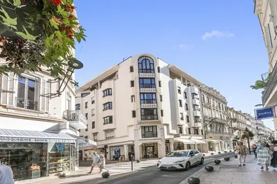 a large white building on a city street with a car at Appartement Cannes Hyper Centre in Cannes