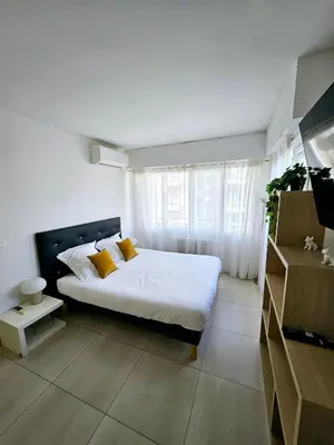 a bedroom with a bed with white sheets and yellow pillows at Appartement 2 pièces, emplacement de rêve Martinez in Cannes