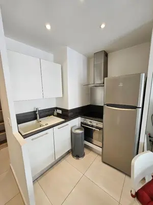 a kitchen with white cabinets and a stainless steel refrigerator at Appartement 2 pièces, emplacement de rêve Martinez in Cannes