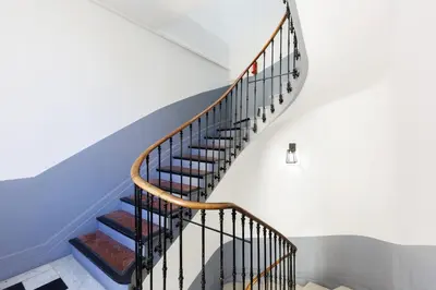 a spiral staircase with black railings in a house at Le Hub Studio central climatisé avec terrasse in Cannes
